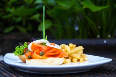 Güzel bir porsiyon somon burger, marul, domates burger ve patates kızartması.