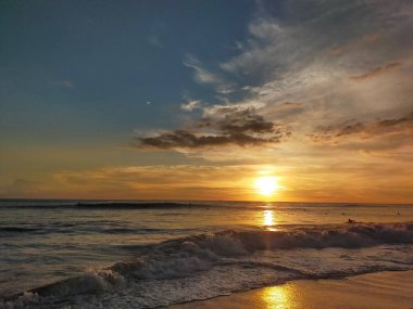 A scenic view of a vast ocean during a bright sunset in an evening hour