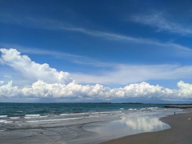 A scenic shot of waves of the sea hitting the shore on a cloudy day