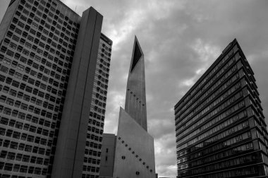 A low angle shot of skyscrapers against cloudy sky in Manchester City, UK in grayscale