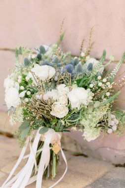 A selective focus shot of a beautiful wedding bouquet leaned on a wall