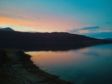 A mesmerizing view of mountains surrounded by water during the sunrise