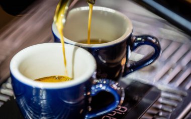 Makinenin fincanlara kahve doldurduğu yakın plan..