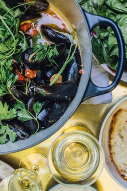 Hollanda fırınında beyaz şarap, domates ve İtalyan maydanozuyla pişirilmiş midyeler.