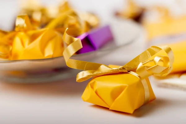 Closeup Shot Candy Wrapped Yellow Paper Golden Ribbon White Table — Stok Foto