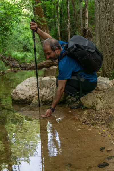 Hombre Barbudo Con Bastón Mochila Bebiendo Agua Arroyo Fondo Paisaje —  Fotos de Stock