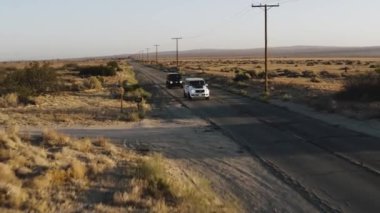 A drone shot of black and white Mercedes-Benz G-class cars driving in the Palmdale desert