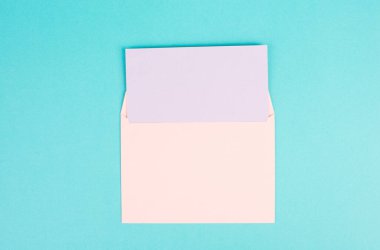 Pembe renkli bir zarf ve içinde kağıt olmayan turkuaz bir zemin, metin için kopyalama alanı, tebrik kartı, iletişim ve duyuru konsepti
