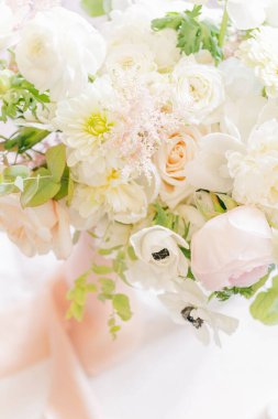 Beyaz bir masanın üzerindeki bir buket beyaz ve pembe çiçeğin yakın çekimi.