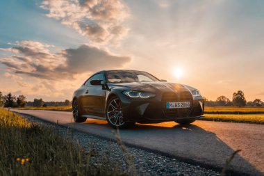 Günbatımında modern bir BMW M4 'ün, Dağ v. lüks spor arabalı görüntüsü birçok sürücünün hayalindeki arabadır.