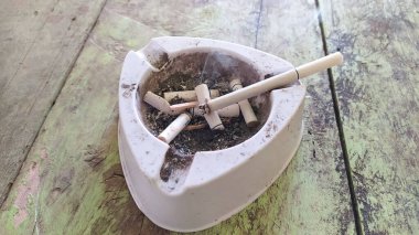 Kül tablasında tütsülenmiş sigara yakın plan çekimi.