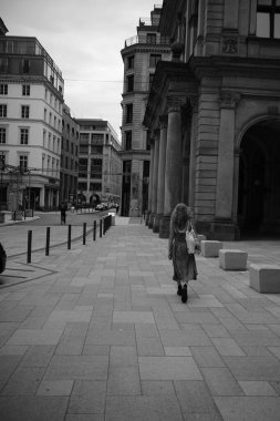 Güneşli bir günde meydanda yürüyen bir kadının gri pulu.