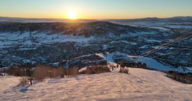 Güneş doğarken karla kaplı parktaki fünikülerin güzel kuş bakışı görüntüsü.