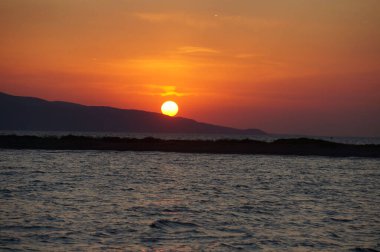 Dalgalanan okyanusun üzerinde nefes kesici turuncu gün batımı manzarası