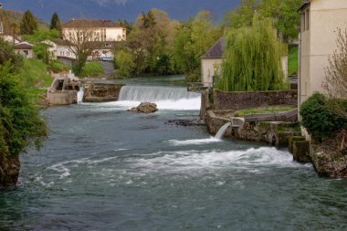 Ağaçlı ve küçük binalı bir parkta güzel bir nehir manzarası.