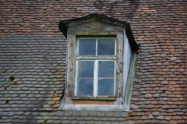 An old gabled dormer rustic window and a tiled roof