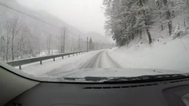 Karlı bir yolun POV 'u. Sürücü bir arabanın içinden kozalaklı ağaçlarla çevrili.