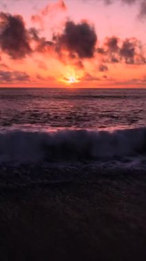 Parlak gün batımında dalgalanan deniz dalgalarıyla çarpıcı bir su manzarası.