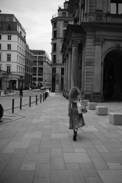 Güneşli bir günde meydanda yürüyen bir kadının gri pulu.