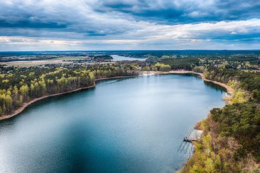 Rozalinowo Gölü 'nün mavi bulutlu gökyüzünün altında yeşil bir manzarayla çevrili insansız hava aracı görüntüsü.