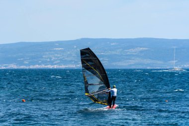 Mavi denizde rüzgar sörfü yapan bir adam.