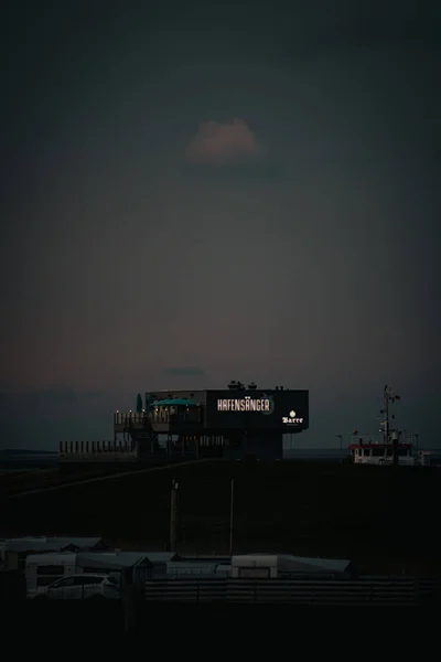 Tiro Vertical Edifício Lado Mar Barco Lado Dele Uma Noite — Fotografia de Stock