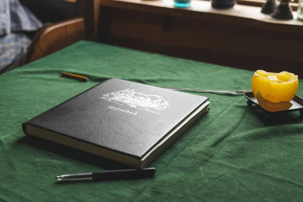 緑のテーブルの上にろうそくの横にノートとボールペンのクローズアップショット — ストック写真