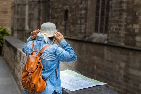 Latin tourist on vacation with her back turned in amazement as she consulted the map in the Gothic Quarter of Barcelona (Spain), travel concept.