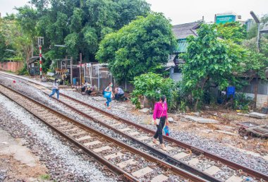 Tayland 'ın güneydoğusundaki Bangkok banliyösündeki bir tren istasyonunun raylarındaki Taylandlılar