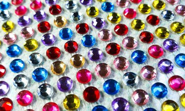 Beyaz bir kumaş üzerinde sıra sıra dizilmiş renkli değerli taşların yakın çekimi