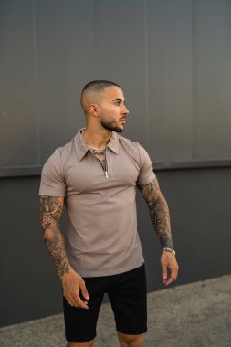 Bej tişörtlü ve siyah şortlu genç bir adamın dikey çekimi.