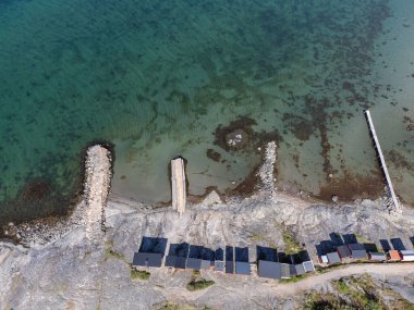 Bird's eye view of archipelago, coastline and sea. Small tiny houses, bathing area, stone piers, turquoise water. Aerial, drone photography.