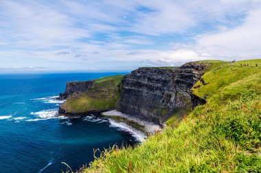 A beautiful view of a cliff near an ocean with a blue sky background