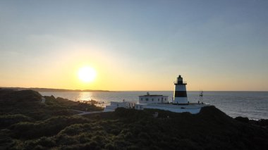 Gün batımında okyanusun kenarında güzel bir deniz feneri manzarası