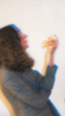 Gri arka planda hareket eden gri ceketli, kıvırcık bir kızın yavaş çekim hızı.