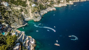 İtalya 'da yeşillik ve binalarla kaplı kayalık Amalfi sahillerine karşı mavi denizin hava manzarası