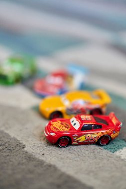 A vertical shallow focus of toy cars on a carpet - Lightning McQueen cartoon characters