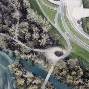 Etrafı yeşilliklerle çevrili resimli yolların ve kırsal kesimde bir nehrin havadan görünüşü.