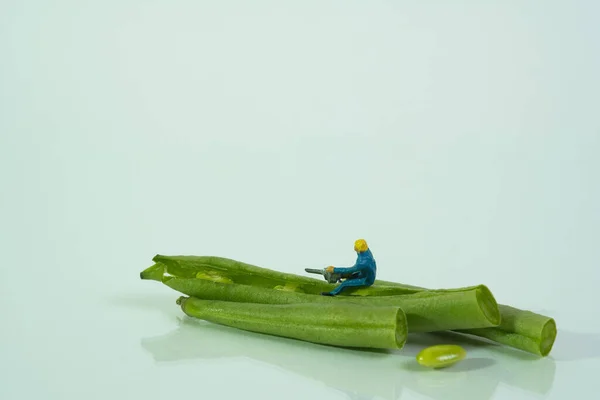 A worker with a chainsaw works on a snap bean. Concept: vegan food