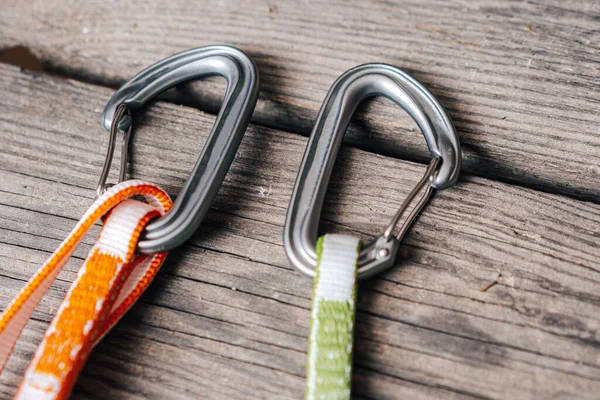Close up detail photo of carabiners and slings. Climbing gear or equipment on a wooden background. Color biners for rock climbing. Sport climbing equi