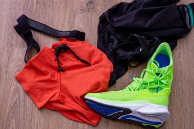 Parlak ahşap bir zeminde spor kıyafetleri, ayakkabılar ve spor saatinin yakın plan çekimi.