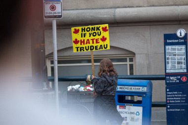 Beyaz kadın, Kanada Başbakanı Justin Trudeau 'ya karşı sarı bir tabela tutuyor