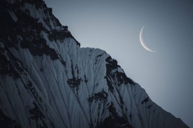 The moon rising above peaks of the Annapurna mountain range in the Himalayas, Nepal