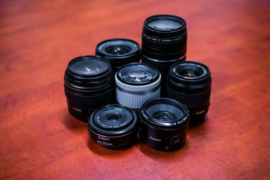A closeup of a group of 7 Canon lenses on a desk in a circle clipart