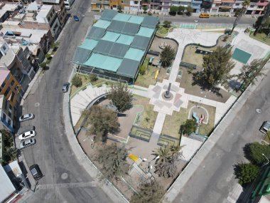 Konut binalarıyla çevrili dar patikalı küçük parkın yüksek açılı görüntüsü..