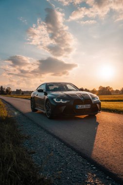 Günbatımında modern bir BMW M4 'ün, Dağ v. lüks spor arabalı görüntüsü birçok sürücünün hayalindeki arabadır.