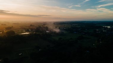 A scenic shot of a colorful sunset peaking through the clouds over the village