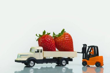 a forklift loads a truck with strawberries, white background. Concept: healthy raw food