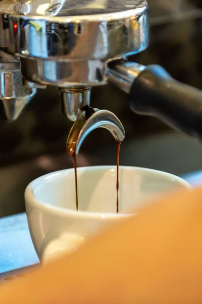 A vertical closeup of the machine pouring coffee into the cup.