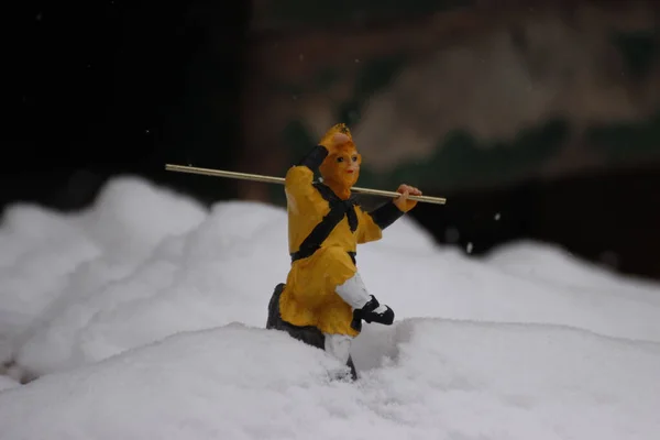 A closeup shot of a Monkey King Chinese figure in the snow